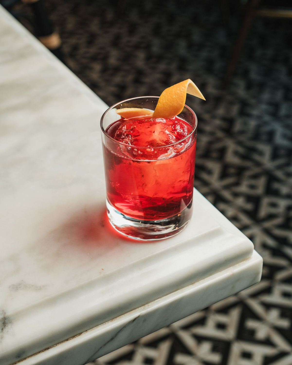 Dark red bitter cocktail with orange on a marble table – photo by Airam Dato-on, Pexels
