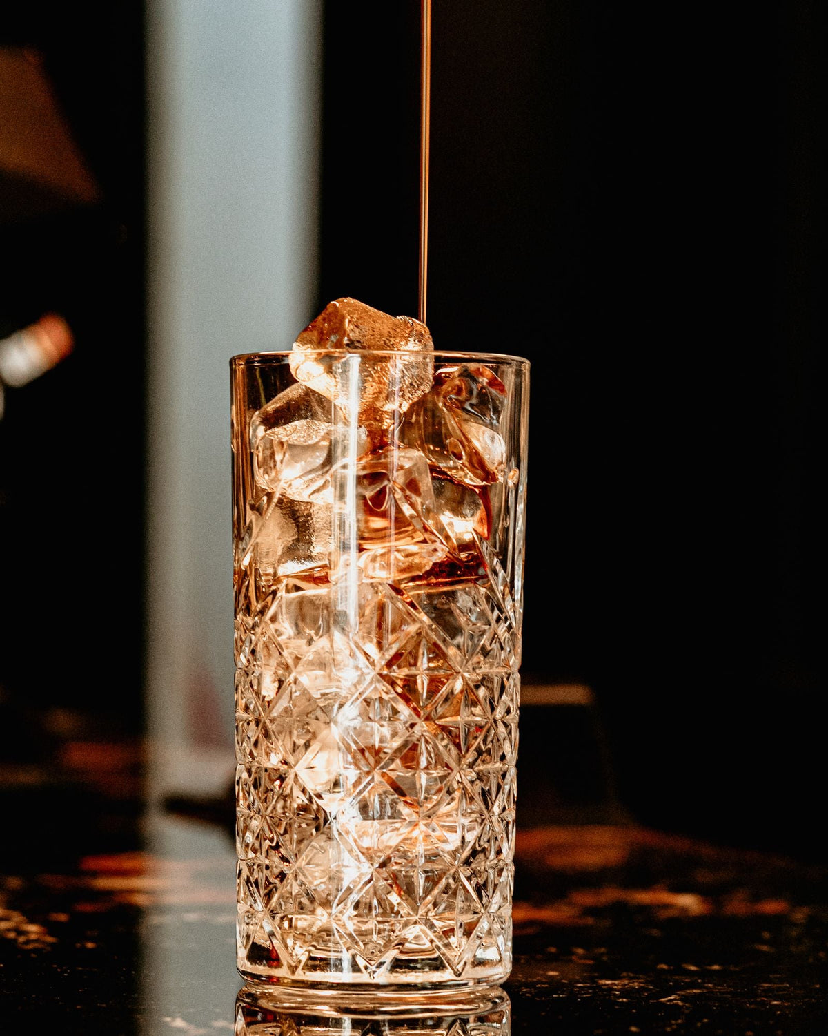 Drink being poured into a crystal glass with ice – photo by Masud Allahverdiyev, Pexels