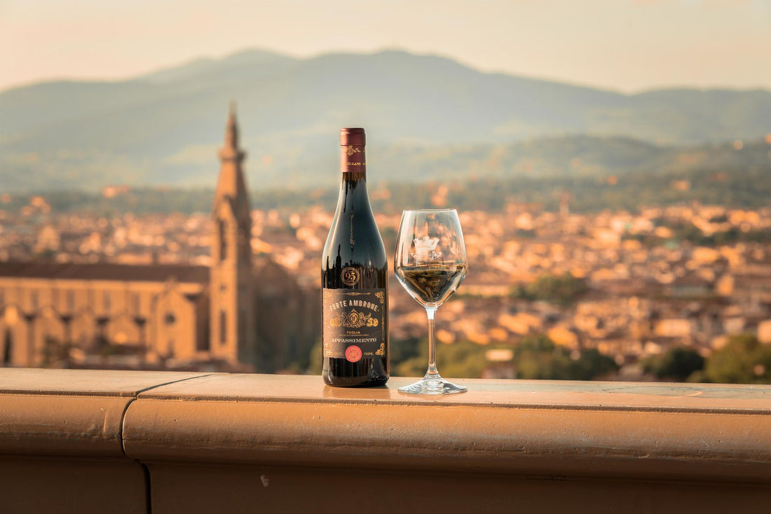 Wine bottle and glass with a Tuscan town behind – photo by Andrea Mosti, Pexels