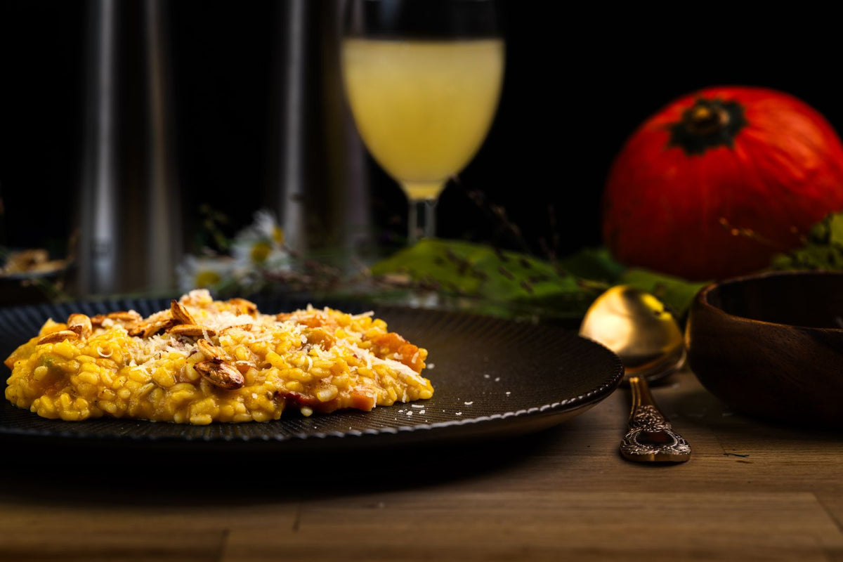 Pumpkin risotto on a dark plate with a pumpkin behind – photo by Jana Ohajdova, Pexels